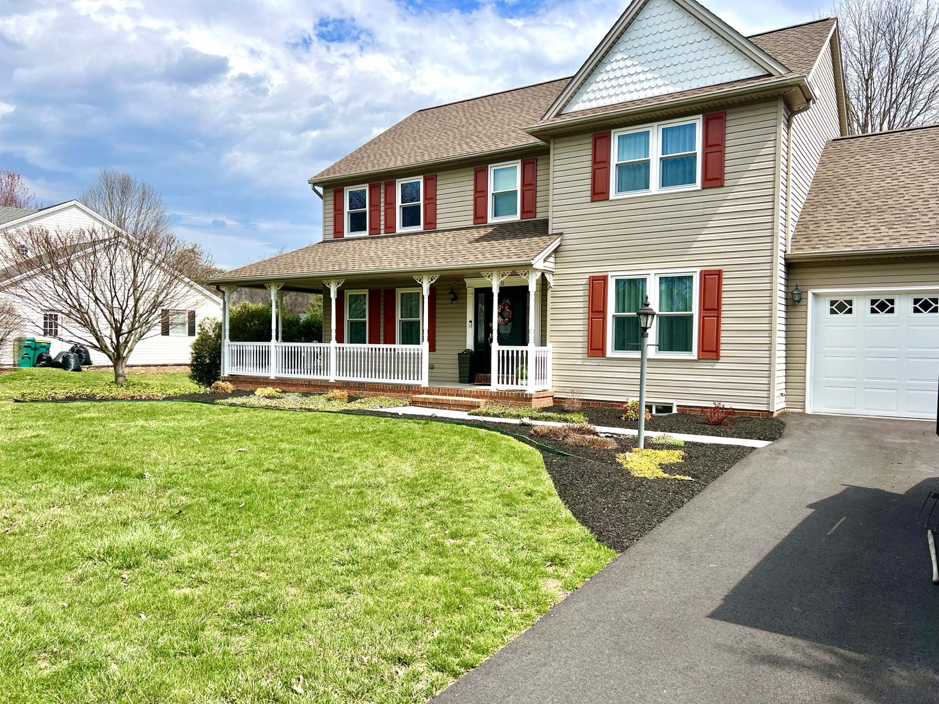Two-story home with fresh landscape beds, green lawn, and covered porch, landscaping in Boiling Springs PA by Landscapes by Landon